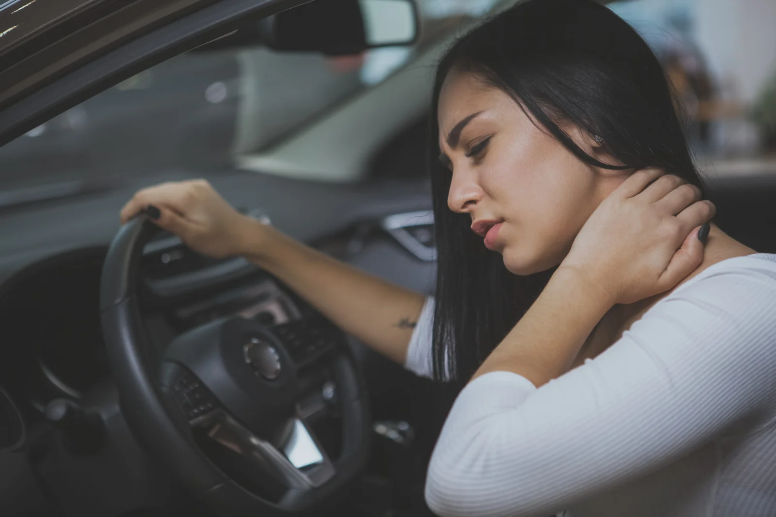 Female driver rubbing her aching neck after being injured in an accident in Miami